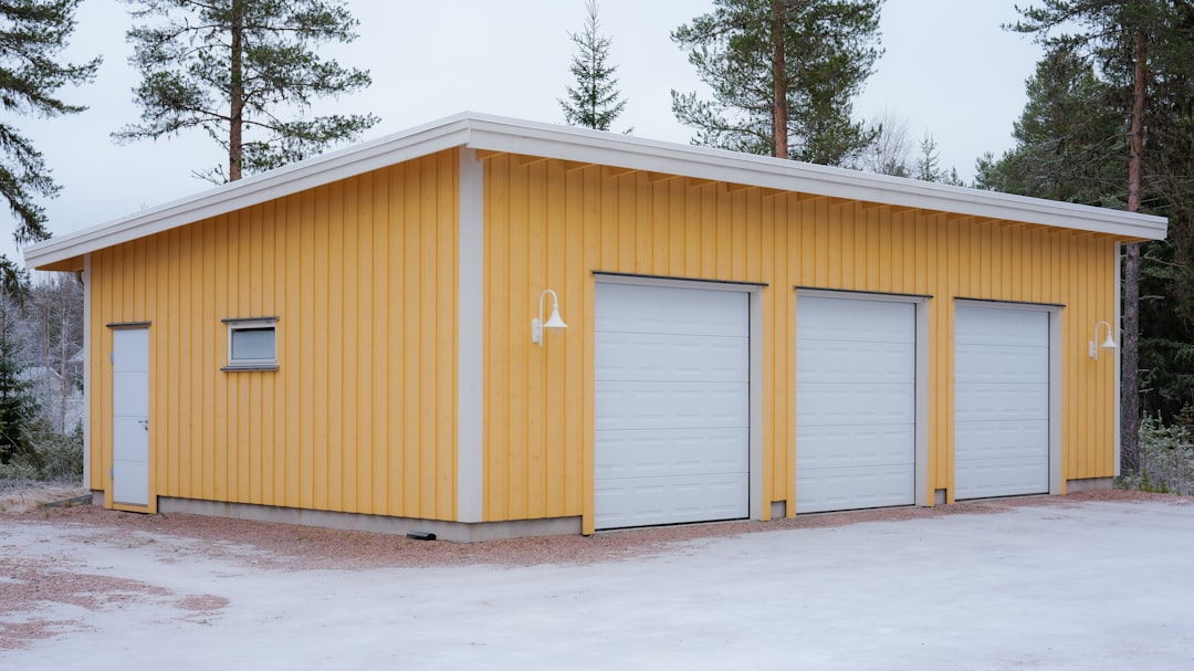 Pienkonevarasto talvella — keltainen halli johon ruohonleikkuri ja saha säilöön